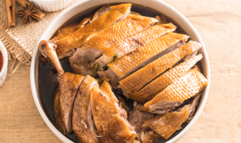 香ばしい皮と柔らかい肉を特徴とする、濃厚なソースに浸かったスライスしたローストダックのボウル。
